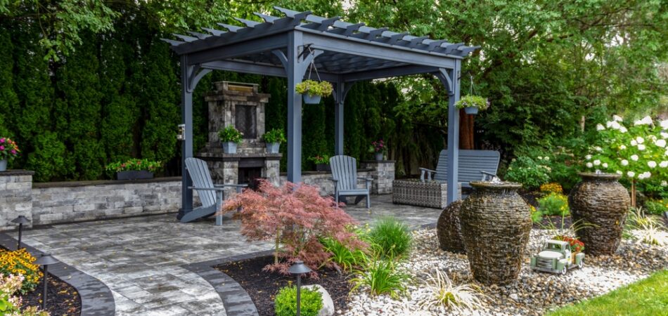 Large,gray,pergola,on,pavers,with,stone,fireplace,and,waterfall